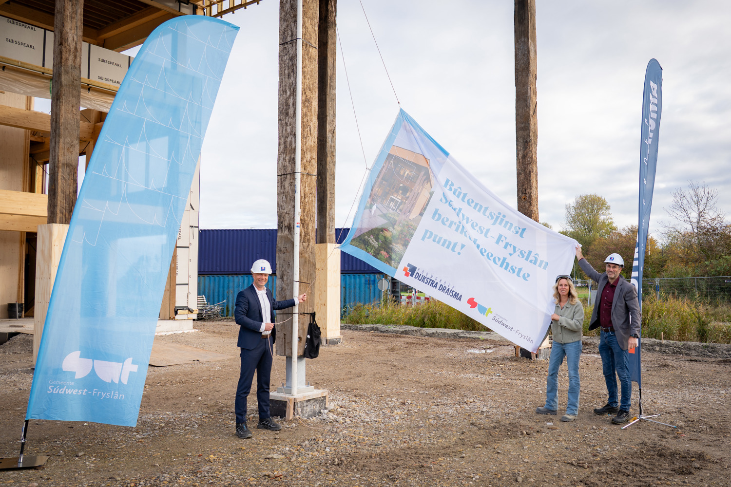 v.l.n.r.: Sjouke Sijtsma hijst de vlag samen met directeur Rixt Smit en wethouder Henk de Boer 